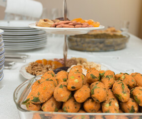 Lentil patties, dry nuts and stuffed olive on white table with dishes ready for event