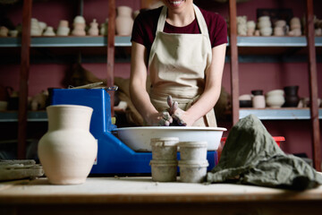Smiling female artist working at pottery wheel