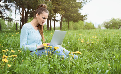 young pretty girl working on laptop outdoors