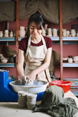 Beautiful woman working at pottery wheel in studio