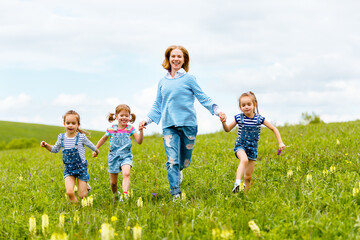 Happy family mother and children daughter girls laughing and running on   meadow in summer