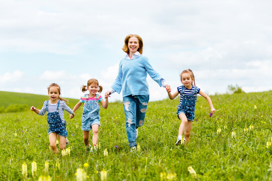 Happy Family Mother And Children Daughter Girls Laughing And Running On   Meadow In Summer