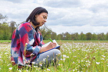 Woman writes in meadow with spring flowers