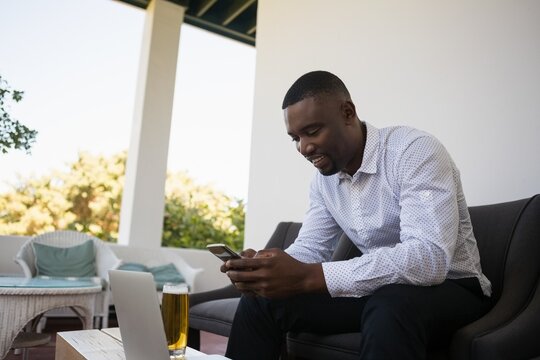 Businessman using phone by beer glass and laptop
