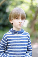Portrait of a schoolboy in a striped sweater in the park