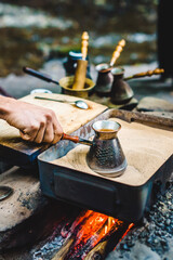 Man is cooking Turkish coffee in the box with sand under live coals