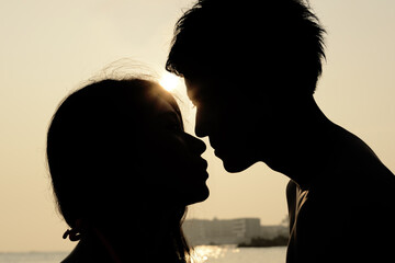 夕日の海でキスをするカップル