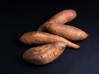 Heap of raw sweet potatoes isolated on black background