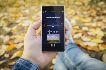 man in the park controlling a drone with the smartphone