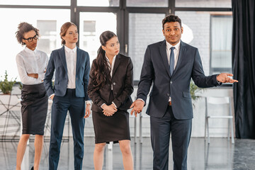 young businesspeople in formalwear posing while standing at modern office, multicultural business team