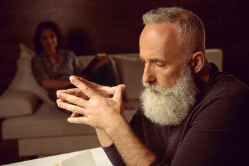tired grey haired man sitting at table in thoughtful pose
