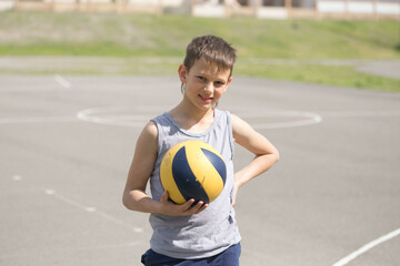 A teenager in a vest holds a ball in his hand