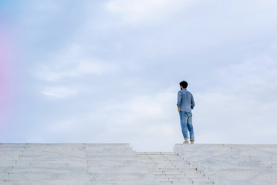 Young man stands alone on top of some steps