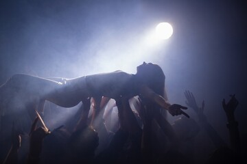 Crowd surfing at a concert - Powered by Adobe