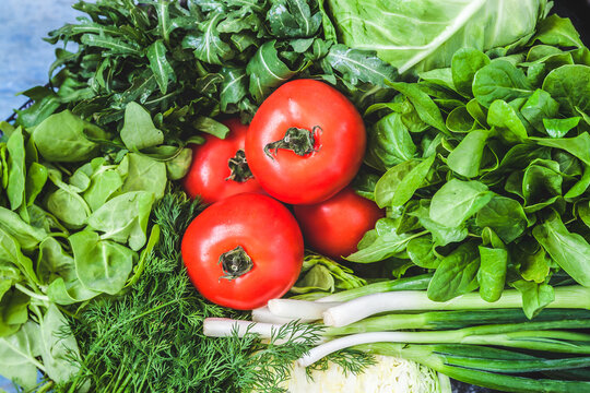 Background of a lot of fresh green different vegetables, herbs and red tomatoes, top view, close-up. The concept of healthy, proper nutrition, diet, detox, cleansing