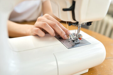 Female tailor threading bobbin into sewing machine case
