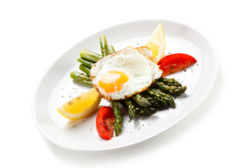 Fried egg with asparagus on white background