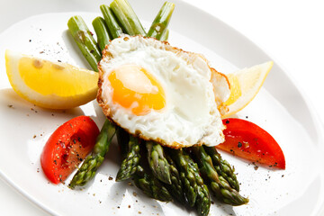Fried egg with asparagus on white background