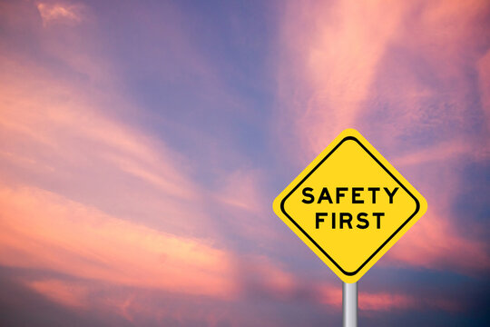 Safety first wording on yellow transportation sign with violet cloud sky background