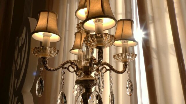 Vintage chandelier with pendants. Sparkling faceted pendulums on the lamp. Lighting iron stand retro. The luxurious interior halls and palaces.