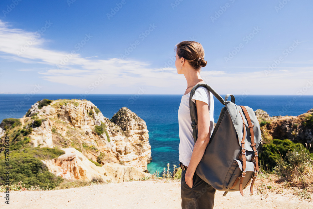 Wall mural Woman traveler looking at the sea, travel and active lifestyle concept