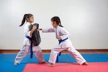 Tuinposter Two little girls demonstrate martial arts working together © 7stock