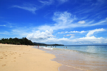 Fototapeta premium Travel to Island Koh Lanta, Thailand. The view on a beach with blue sea, cloudy sky and white sand on a sunny day.