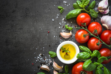 Ingredients for cooking. Vegetables olive oil tomato basil on black. Top view copy space.