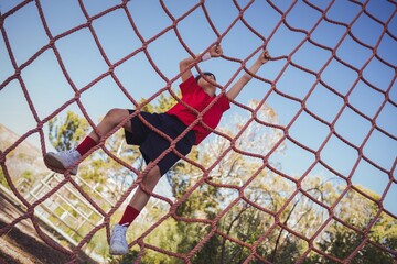 Obraz na płótnie Canvas Boy climbing a net during obstacle course training