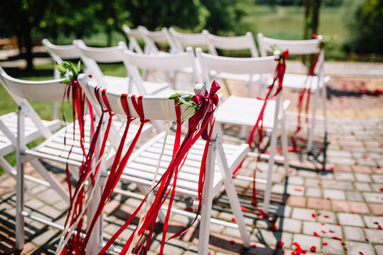Red ribbons hang from white chairs standing outside