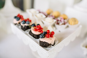 White cookies decorated with berries stand on white dish