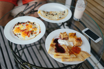 White plates with delicious breakfast and iPhone on glass plate