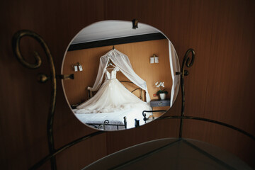 Wedding dress lies on the bed and reflects in the mirror