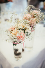 Bouquets of pinks and tiny daisies stand on white table
