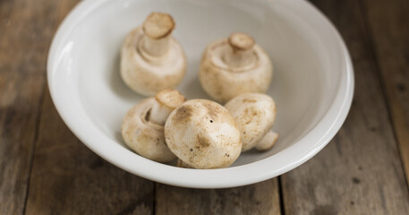 Fototapeta na wymiar Raw mushrooms in a bowl on a wooden table