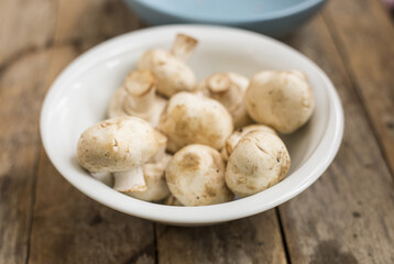 Raw mushrooms in a bowl on a wooden table