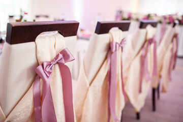 Chairs decorated with violet ribbons stand at dinner tables