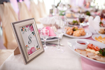 Number eight put in a frame stands on pink dinner table