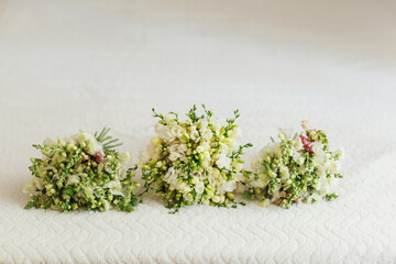 Green wedding bouquets lie on white blanket