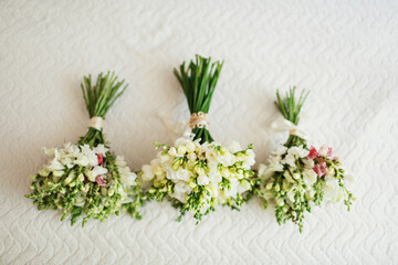 Green wedding bouquets lie on white blanket