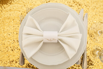 White napkin lies on a plate on golden cloth