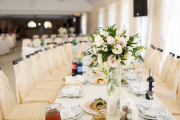 White bouquet stands in the center of dinner table