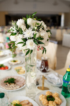 White bouquet stands in the center of dinner table