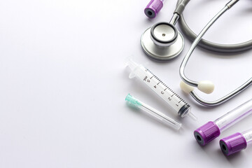 closeup blood sample tubes, syringe and stethoscope on white background. soft-focus and over light
