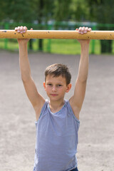 Fototapeta premium A teenager in a T-shirt is engaged in gymnastics on a horizontal bar