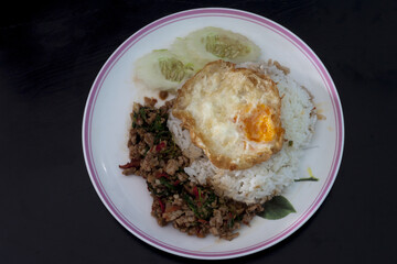 Basil Pork with Egg on wood black color. Full View.