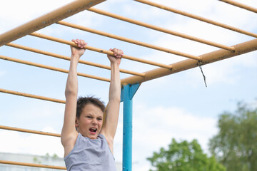 Fototapeta premium A teenager in a T-shirt is engaged in gymnastics on a horizontal bar