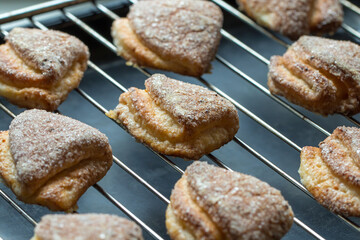 Many puff pastry cookies on metal grid