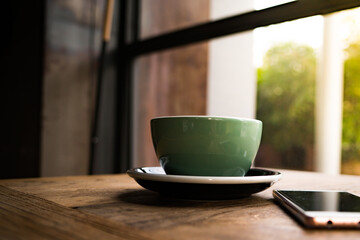 A coffee cup with the smart phone on the wooden table