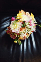 Bright wedding bouquet of roses and chrysanthemums lie on leather chair
